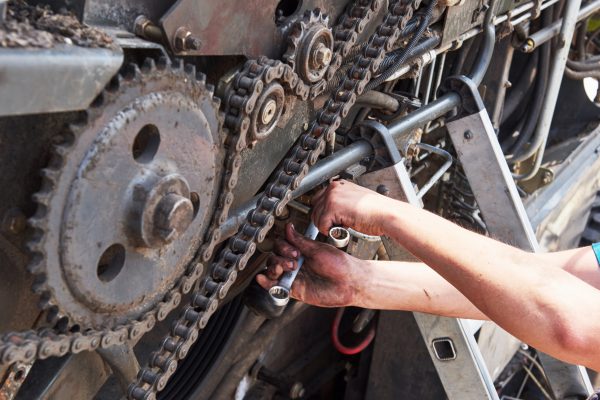Combine machine service, mechanic repairing motor outdoors.